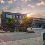 Das Gebäude der Solar-Pur AG mit Solarpanelen und Ladestationen für Elektrofahrzeuge.