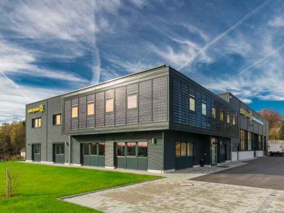Ein modernes Bürogebäude mit großen Fenstern und einer strukturierten Fassade in einem klaren Himmel.