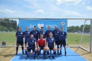 Eine Fußballmannschaft steht vor einem Tor mit einem Banner im Hintergrund.