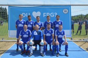 Eine Fußballmannschaft in blauen Trikots steht vor einem Tor auf dem Spielfeld.