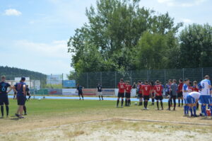 Fußballspieler in roten und blauen Trikots auf dem Spielfeld während eines Spiels.