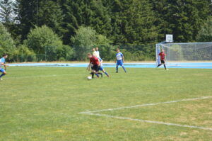 Zwei Spieler im Wettkampf um den Ball auf einem Fußballfeld mit Tor im Hintergrund.