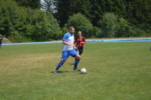 Ein Fußballspieler in blauen Trikots führt den Ball auf einem grünen Spielfeld.