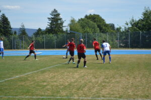 Fußballspieler in roten und weißen Trikots auf einem Sportplatz während eines Spiels.