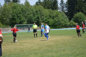 Spieler in roten und blauen Trikots während eines Fußballspiels auf einem Rasenfeld.