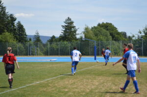Fußballspieler in blauen und roten Trikots auf einem Spielfeld während eines Spiels.