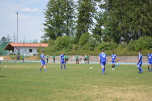 Fußballspieler in blauen Trikots auf einem Spielfeld während eines Spiels.