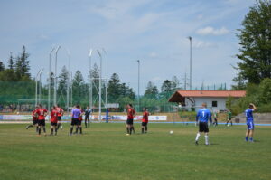 Fußballspieler in roten und blauen Trikots auf einem Spielfeld während eines Spiels.