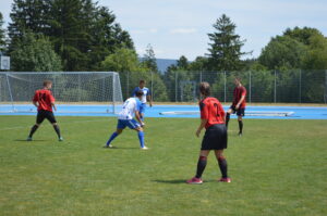 Zwei Gruppen von Fußballspielern in roten und blauen Trikots auf einem Spielfeld.
