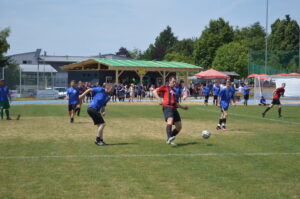 Zwei Gruppen von Fußballspielern in blauen und roten Trikots auf einem Rasenplatz während eines Spiels.