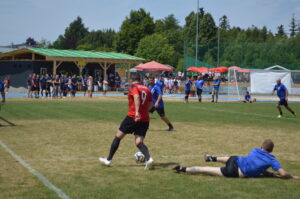 Ein Fußballspieler in rotem Trikot mit der Nummer 9 dribbelt den Ball während eines Spiels auf einem Rasenplatz.