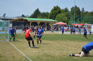 Spieler in roten und blauen Trikots während eines Fußballspiels auf einem Rasenplatz.