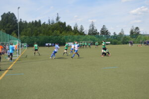 Zwei Fußballmannschaften spielen auf einem Kunstrasenplatz während eines Spiels.