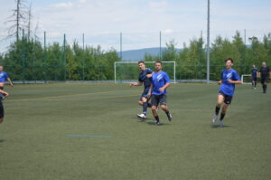 Spieler in blauen Trikots laufen auf einem Kunstrasenplatz während eines Fußballspiels.