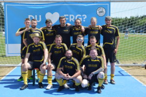 Eine Fußballmannschaft in gelben Trikots steht vor einem Tor auf dem Spielfeld.