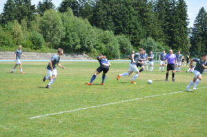 Mehrere Fußballspieler in einem Spiel auf einem grünen Rasenfeld mit einem Ball.