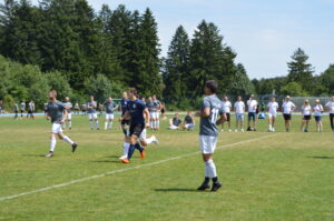 Spieler in grauen und schwarzen Trikots während eines Fußballspiels auf einem Rasenplatz.