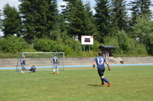 Ein Fußballspieler mit der Nummer 12 läuft auf das Tor zu, während ein Torwart bereit ist.