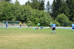 Spieler in blauen und grünen Trikots auf einem Fußballfeld während eines Spiels.