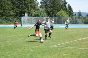 Zwei Spieler in Schwarz und Grau kämpfen um den Ball auf einem Fußballfeld.