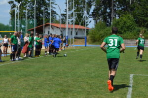 Fußballspieler in grünen Trikots auf einem Sportplatz während eines Spiels.