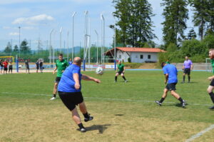 Eine Gruppe von Spielern in blauen und grünen Trikots spielt Fußball auf einem Rasenplatz.