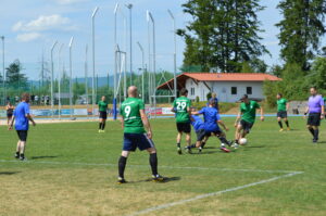 Zwei Fußballmannschaften spielen auf einem Rasenplatz, während ein Spieler den Ball dribbelt.