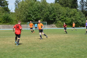 Fußballspieler in orange und rot auf einem Rasenplatz während eines Spiels.