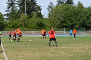 Zwei Gruppen von Fußballspielern in roten und orangen Trikots auf einem Spielfeld während eines Spiels.