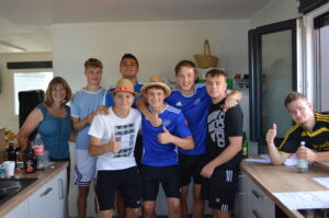 Eine Gruppe von sieben Jugendlichen steht in einer modernen Küche und posiert für ein Foto.