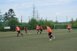Fußballspieler in orange und schwarz auf einem Kunstrasenplatz während eines Spiels.