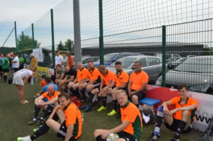 Fußballspieler in orange Trikots sitzen auf einer Bank am Spielfeldrand.
