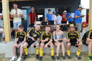 Fünf Fußballspieler in gelben Trikots sitzen zusammen und posieren für ein Foto.