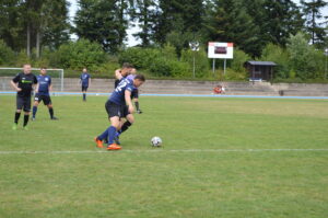 Zwei Fußballspieler in blauen Trikots stehen auf einem Rasenfeld während eines Spiels.