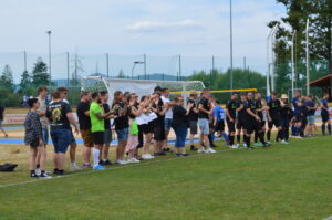 Gruppe von Zuschauern und Spielern, die auf einem Fußballfeld stehen und applaudieren.