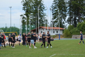 Gruppe von Fußballspielern in schwarzen Trikots, die sich auf dem Spielfeld umarmen.