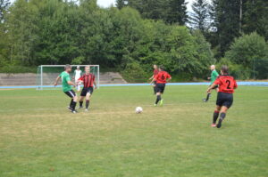 Zwei Gruppen von Fußballspielern in roten und grünen Trikots auf einem Spielfeld.