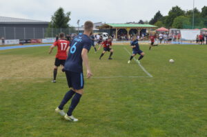 Spieler in blauen Trikots während eines Fußballspiels auf einem Rasenplatz.