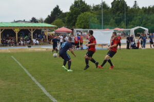 Zwei Fußballspieler in blauen und roten Trikots während eines Spiels auf einem Rasenplatz.