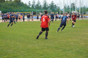 Zwei Fußballspieler in roten und blauen Trikots während eines Spiels auf einem Rasenfeld.