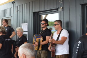 Zwei Musiker, einer mit Akkordeon und der andere mit Gitarre, spielen in einer Gruppe von Menschen.