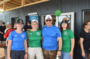 Vier Personen in Sportkleidung, zwei tragen blaue und zwei grüne T-Shirts mit Kappen.