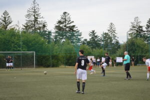 Spieler in schwarzer und weißer Fußballausrüstung auf einem Sportplatz während eines Spiels.