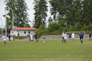 Zwei Mannschaften spielen Fußball auf einem Sportplatz mit einem Ball im Spiel.