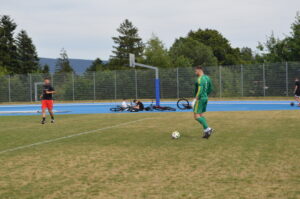 Ein Fußballspieler in grüner Ausrüstung steht auf dem Spielfeld und bereitet sich auf einen Schuss vor.