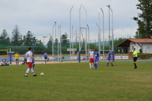 Zwei Gruppen von Fußballspielern auf einem Spielfeld, eine in roten und die andere in blauen Trikots.