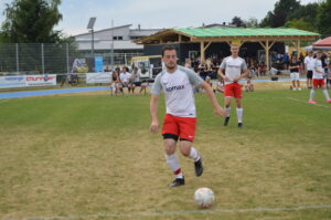 Ein Fußballspieler in einem weißen und roten Trikot, der den Ball auf dem Spielfeld spielt.