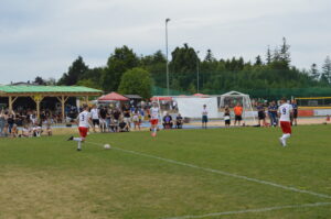 Drei Fußballspieler in roten und weißen Trikots auf einem Spielfeld während eines Spiels.