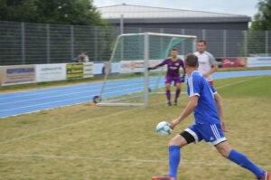 Ein Spieler in blauer Uniform bereitet sich darauf vor, den Ball während eines Fußballspiels zu spielen.