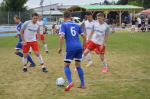 Zwei Fußballmannschaften spielen auf einem Rasenplatz, ein Spieler dribbelt den Ball.